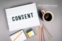 The word consent in a lightbox with pencils and a mug of coffee