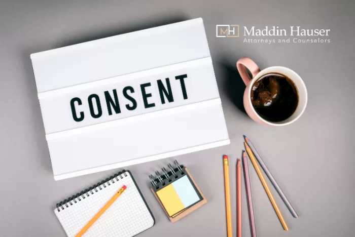 The word consent in a lightbox with pencils and a mug of coffee